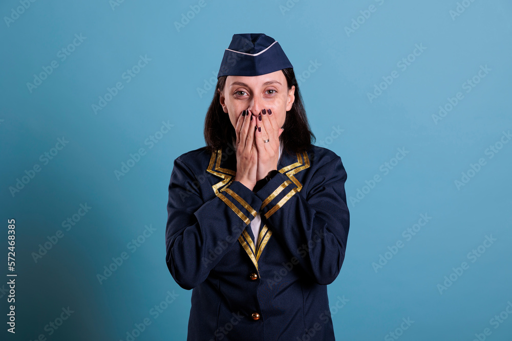 Flight attendant covering mouth with hands, showing speak no evil gesture, looking at camera. Airplane stewardess with covered lips front view, censorship, keeping silence concept