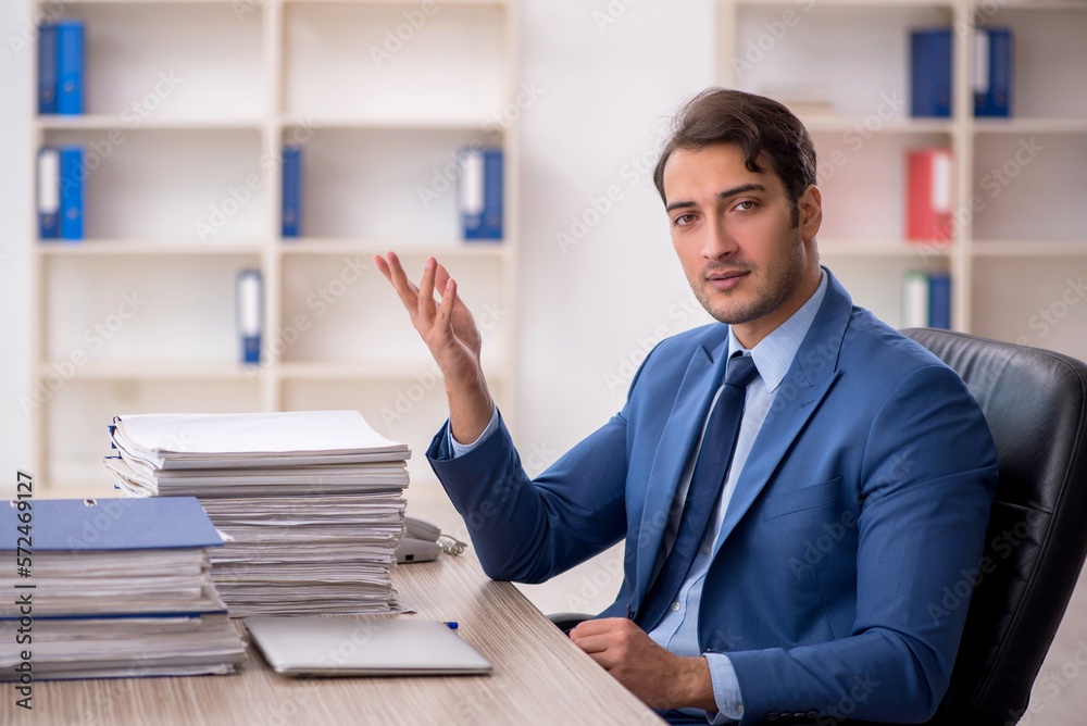 Young male employee and too much work in the office Young male employee and too much work in the office