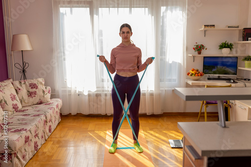 Online workout. Teen girl doing Sport exercise at home, watching tutorials on a laptop. How to keep fit indoors