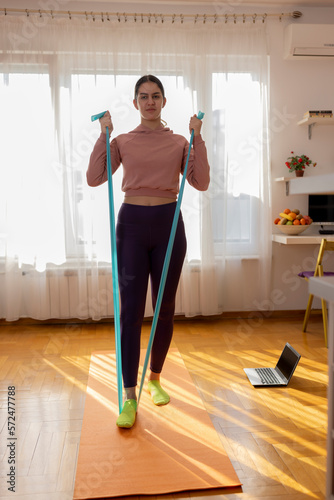 Online workout. Teen girl doing Sport exercise at home, watching tutorials on a laptop. How to keep fit indoors