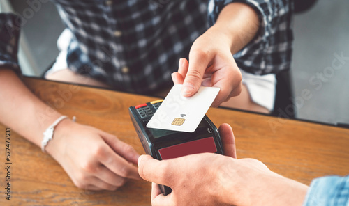 Person hand holding a credit card next to the card reader paying for his shopping 