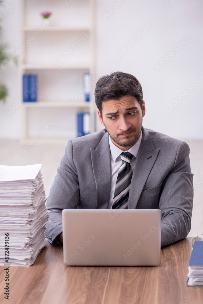 Young male employee and too much work in the office Young male employee and too much work in the office