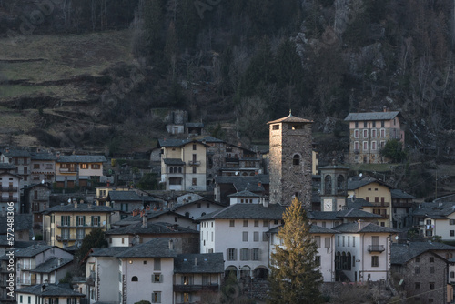 Little village of Gromo, Lombardy, Italy - February 2023. The last rays of the setting sun illuminate the village