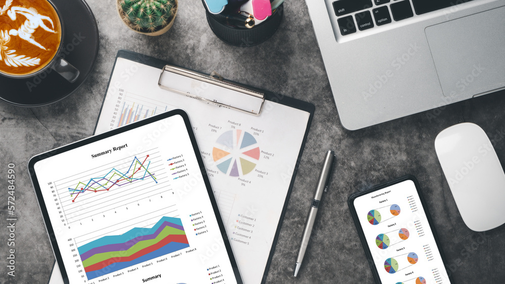 Obraz premium Tablet and smartphone with charts and reports on wooden desk workplace. Top view flat lay