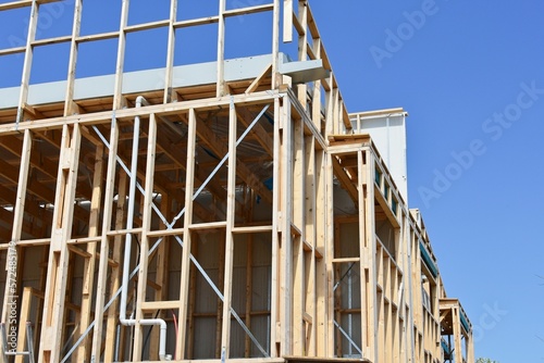 A new house under construction with framing and blue sky.