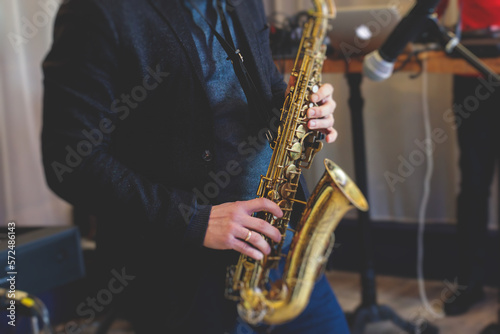 Concert view of saxophonist, a saxophone sax player with vocalist and musical band during jazz orchestra show performing music on stage in the scene lights