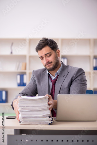 Young male employee unhappy with excessive work in the office