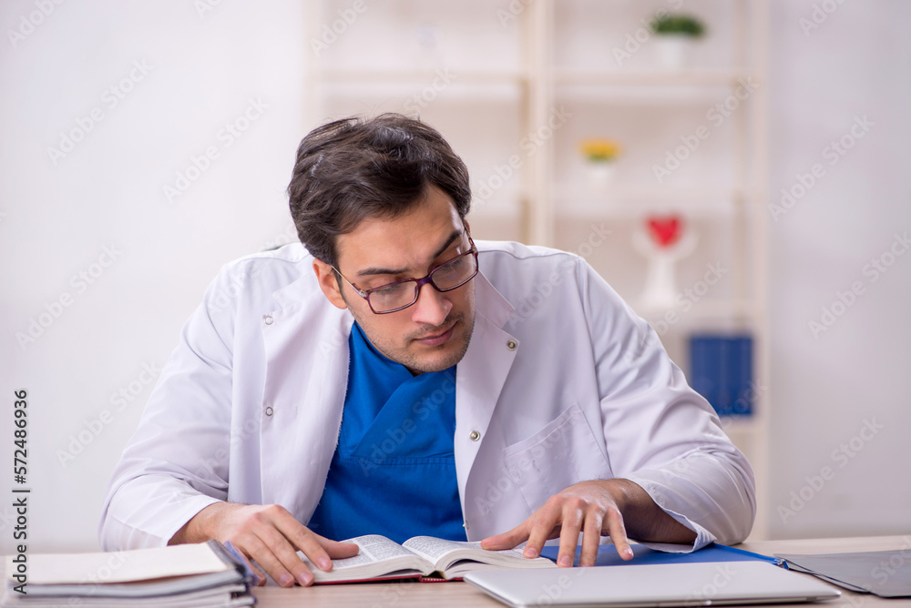 Young male doctor student reading book in the clinic