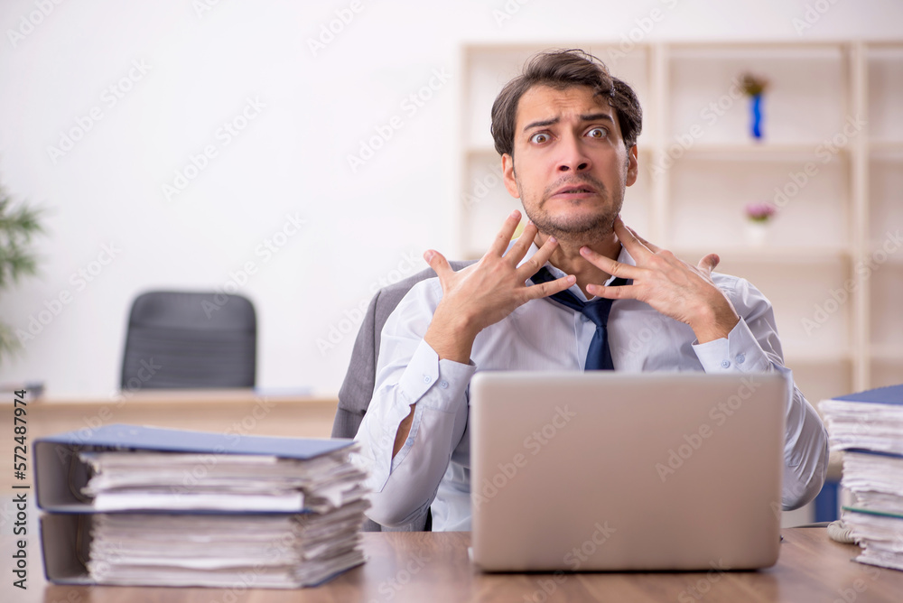 Young male employee and too much work in the office Young male employee and too much work in the office