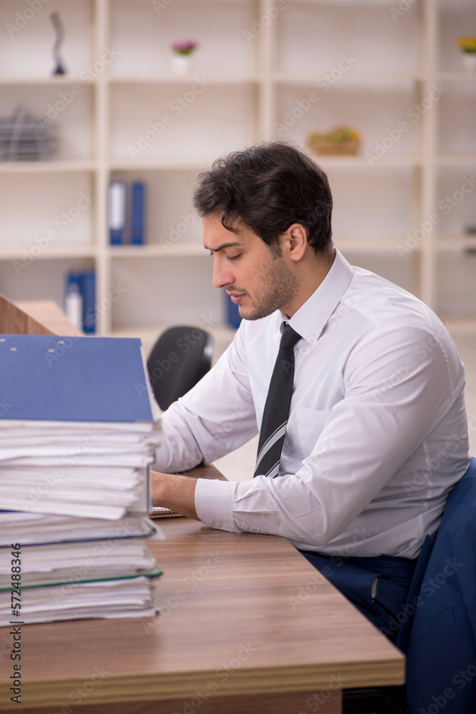 Young male employee and too much work in the office Young male employee and too much work in the office