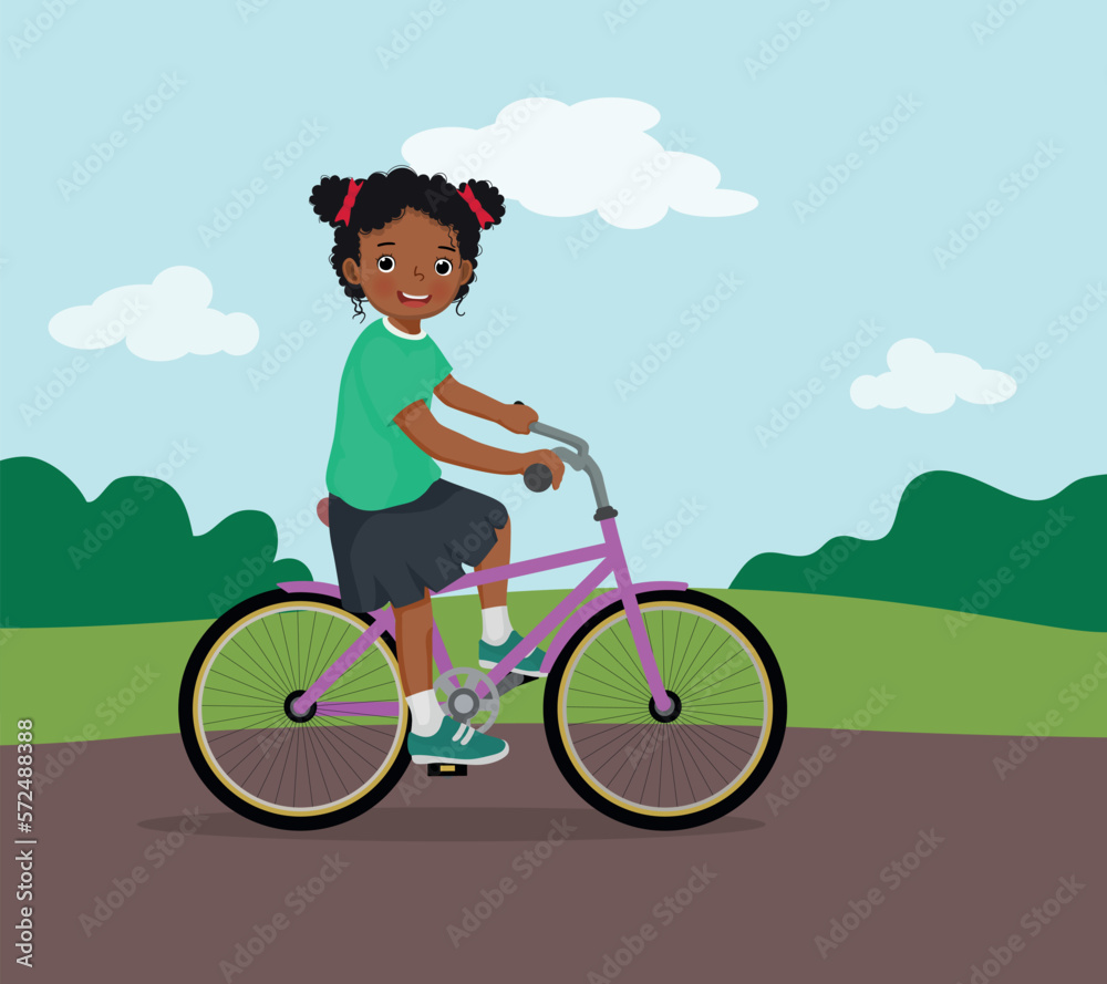 happy little African girl riding a bike having fun in the park on sunny day