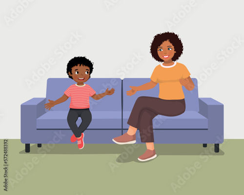 Young African mother talking to her son sitting on sofa giving advises encouragement and support 