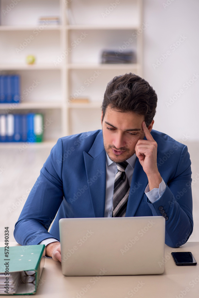 Young male employee and too much work in the office Young male employee and too much work in the office