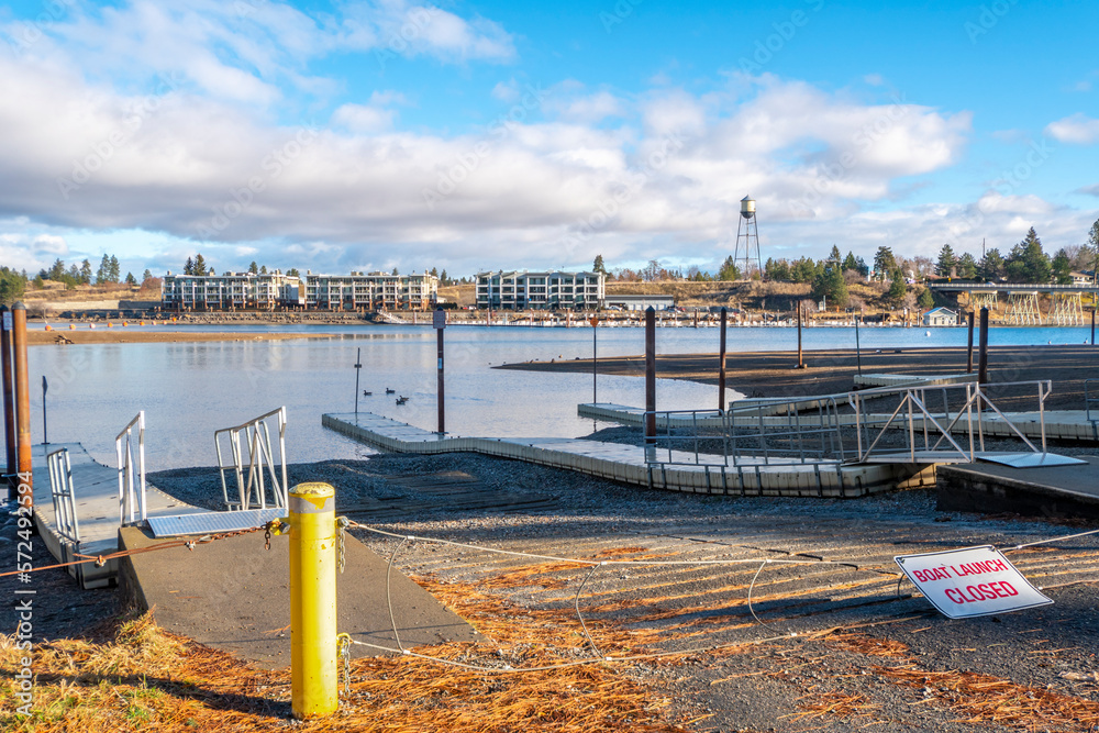 The closed boat ramp and launch at Q'emiln Park along the Spokane River in Post Falls, Idaho, USA, during late autumn, with waterfront condominiums across the river.	