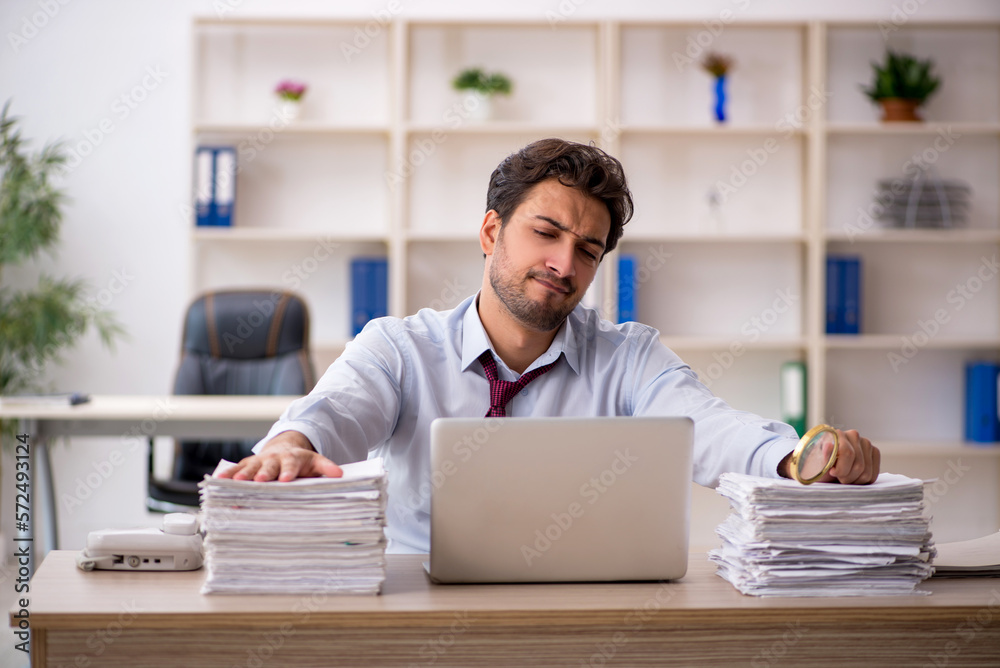 Young male employee and too much work in the office Young male employee and too much work in the office