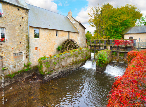 The water mill on the River Aure in the medieval town of Bayeux on the Normandy Coast of France, with bold autumn colors 