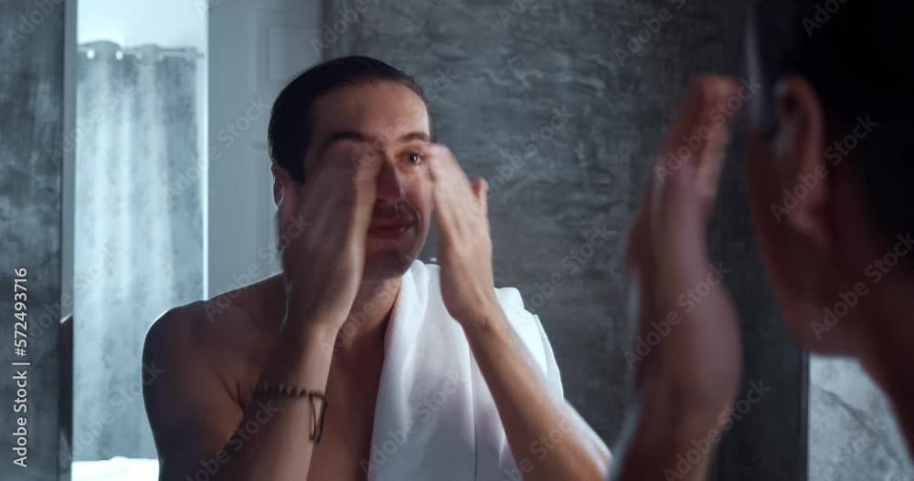 Happy caucasian man looking in the mirror in the bathroom, combing his ...