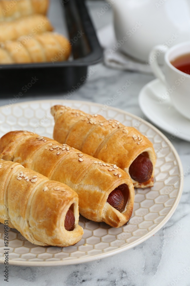 Delicious sausage rolls and hot drink on white marble table, closeup Delicious sausage rolls and hot drink on white marble table, closeup