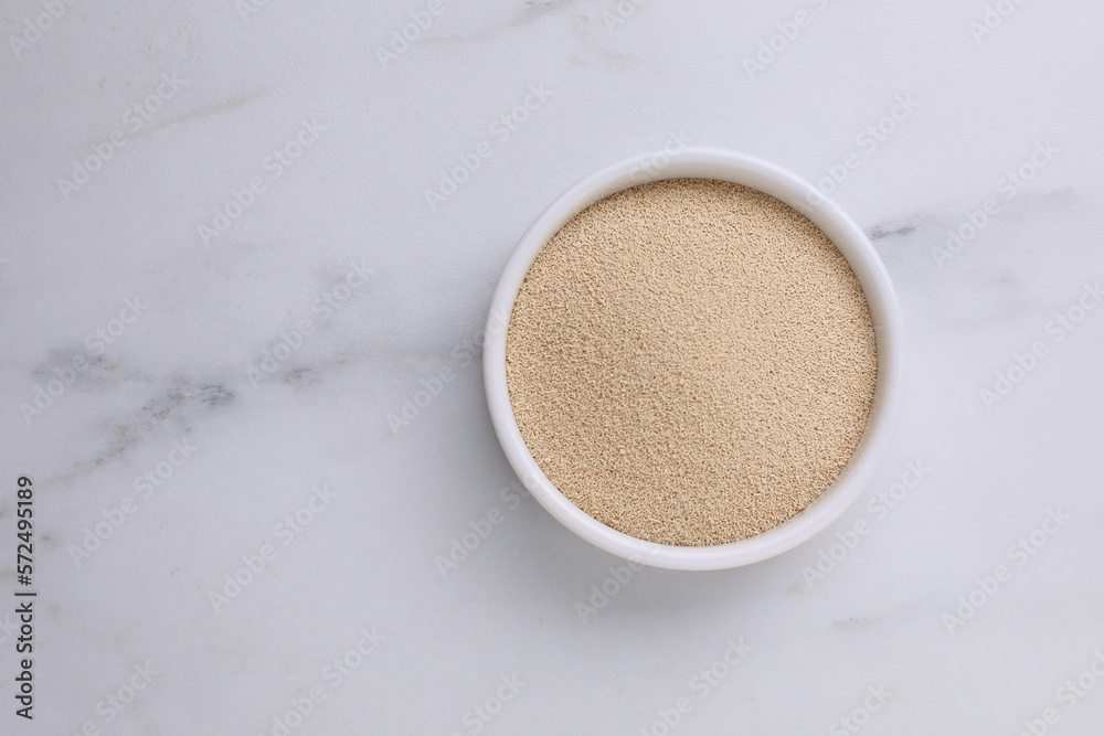 Bowl of active dry yeast on white marble table, top view. Space for text Bowl of active dry yeast on white marble table, top view. Space for text