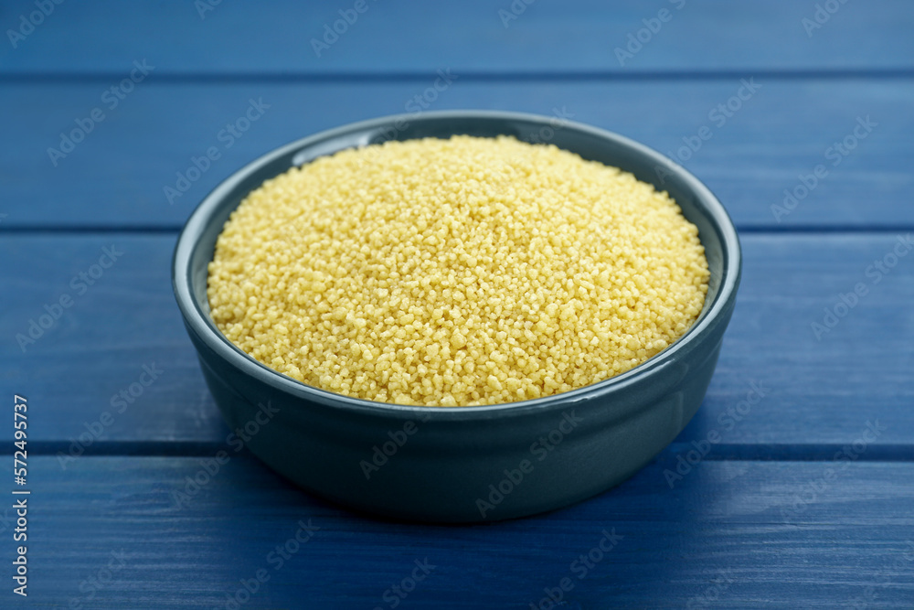 Bowl of raw couscous on blue wooden table, closeup Bowl of raw couscous on blue wooden table, closeup