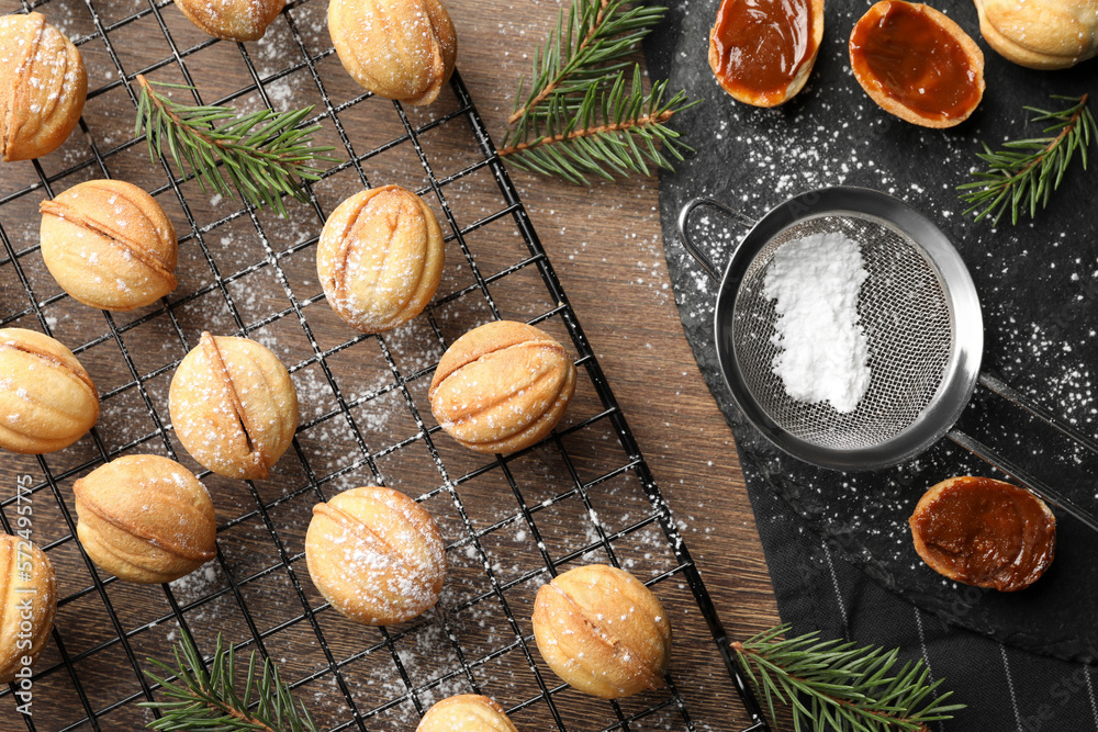 Fototapeta premium Homemade walnut shaped cookies with boiled condensed milk and fir branches on wooden table, flat lay