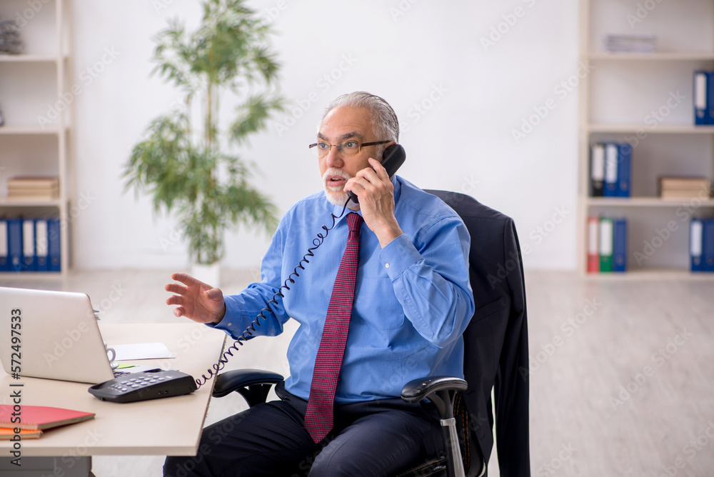 Old male employee working in the office Old male employee working in the office