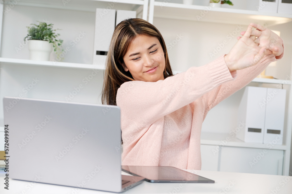 Young asian woman stretching body for relaxing while working with laptop computer at her desk, home office lifestyle Young asian woman stretching body for relaxing while working with laptop computer at her desk, home office lifestyle