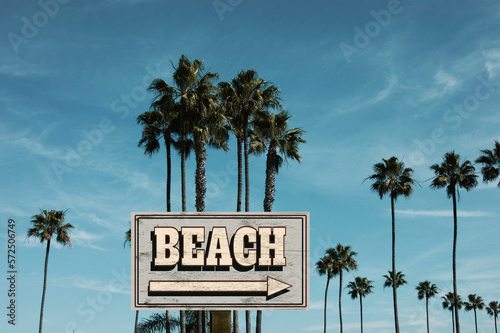 Aged wooden beach sign with palm trees