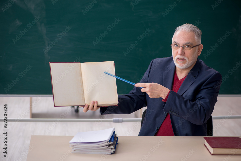 Old male teacher sitting in the classroom Old male teacher sitting in the classroom