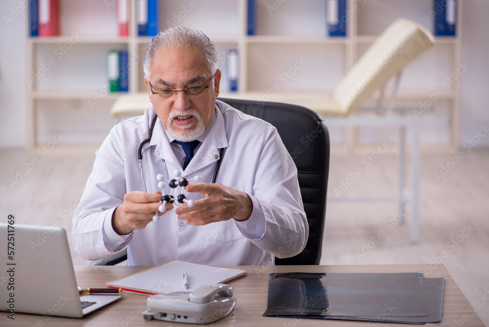 Old male doctor lecturer holding molecular model
