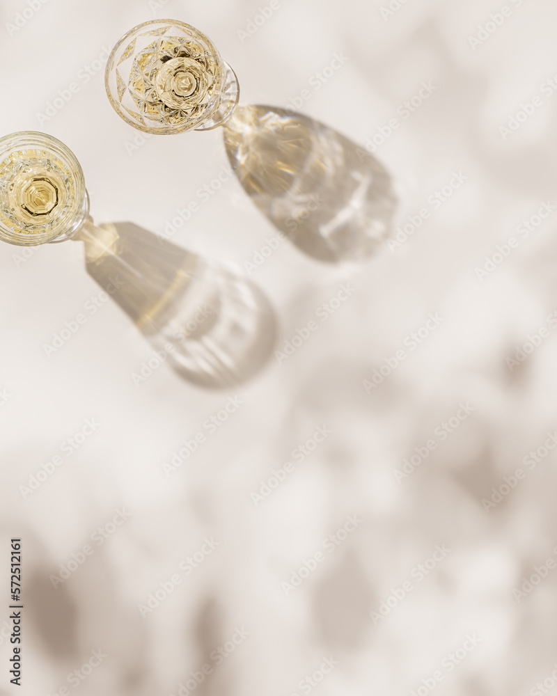 White wine in crystal transparent fashion glasses with leaves shadow at sunlight, beige background and beautiful light, creative summer alcohol drink minimal concept, copyspace, top view White wine in crystal transparent fashion glasses with leaves shadow at sunlight, beige background and beautiful light, creative summer alcohol drink minimal concept, copyspace, top view