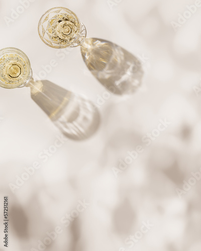 White wine in crystal transparent fashion glasses with leaves shadow at sunlight, beige background and beautiful light, creative summer alcohol drink minimal concept, copyspace, top view