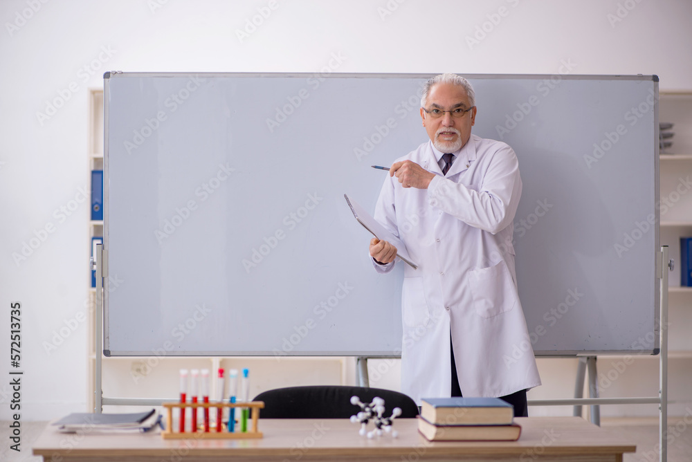 Old male chemistry teacher in the classroom