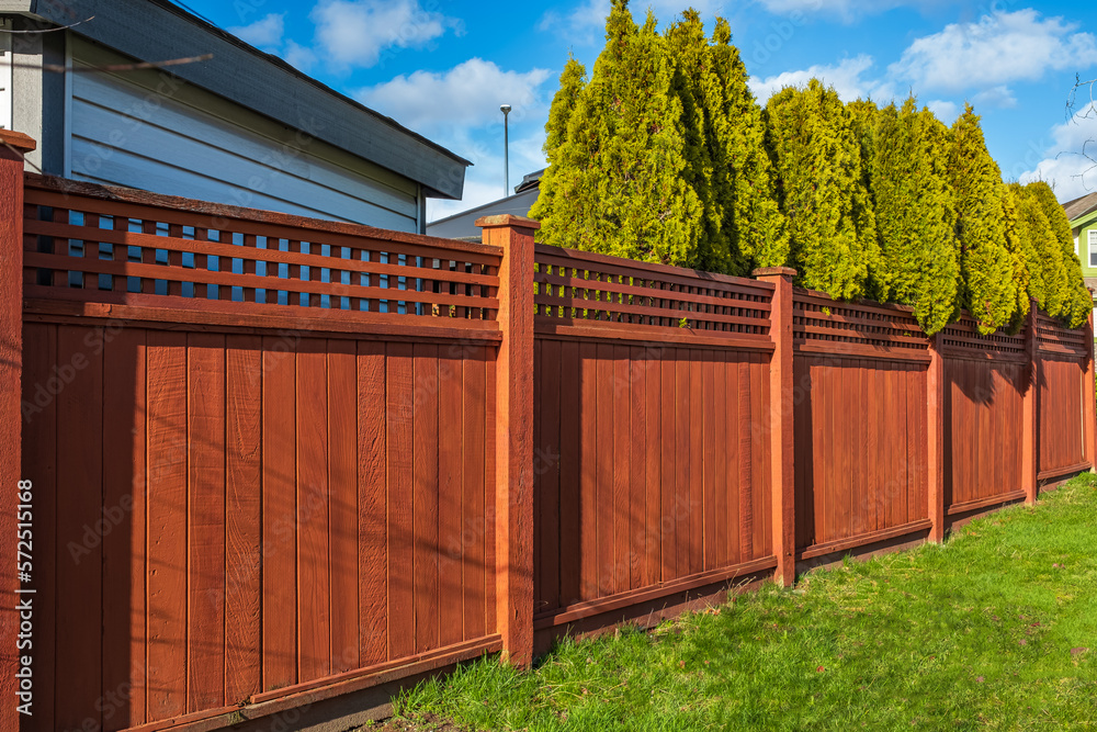 Nice new wooden fence around house. Wooden fence with green lawn. Street photo