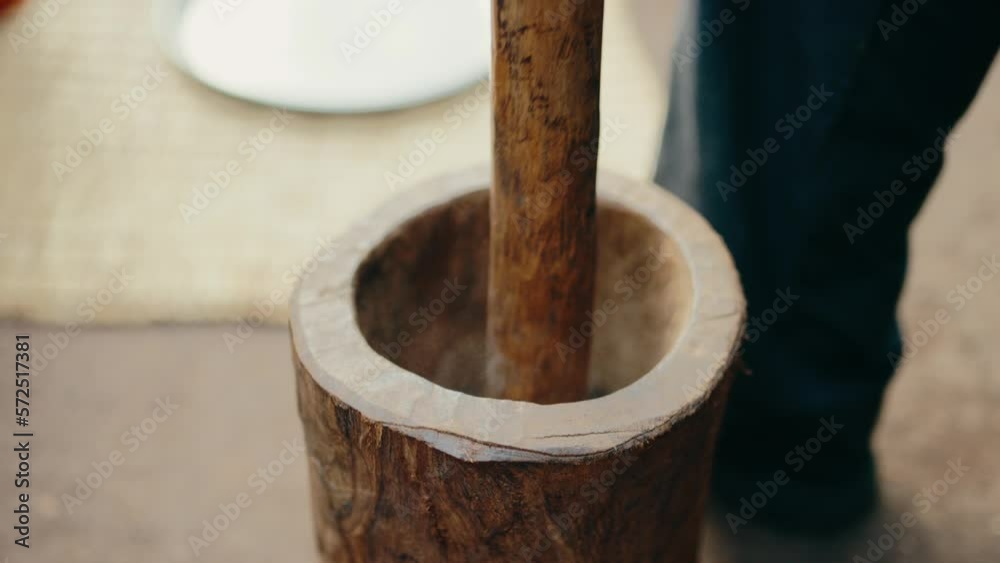 Close-up view of wooden mortar and pestle used to manually grind coffee beans