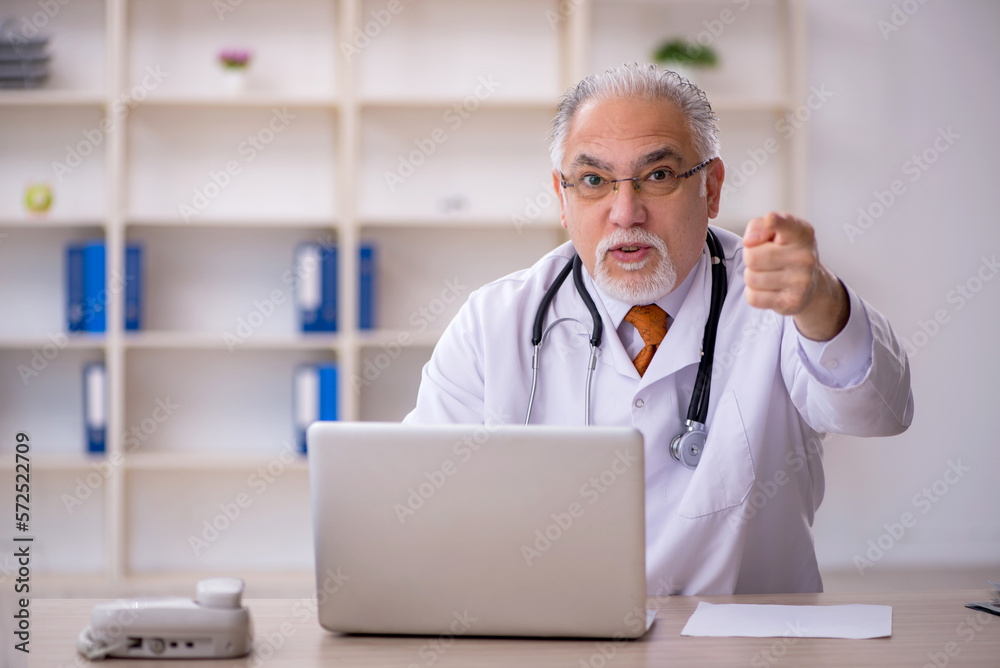 Old male doctor working in the clinic Old male doctor working in the clinic