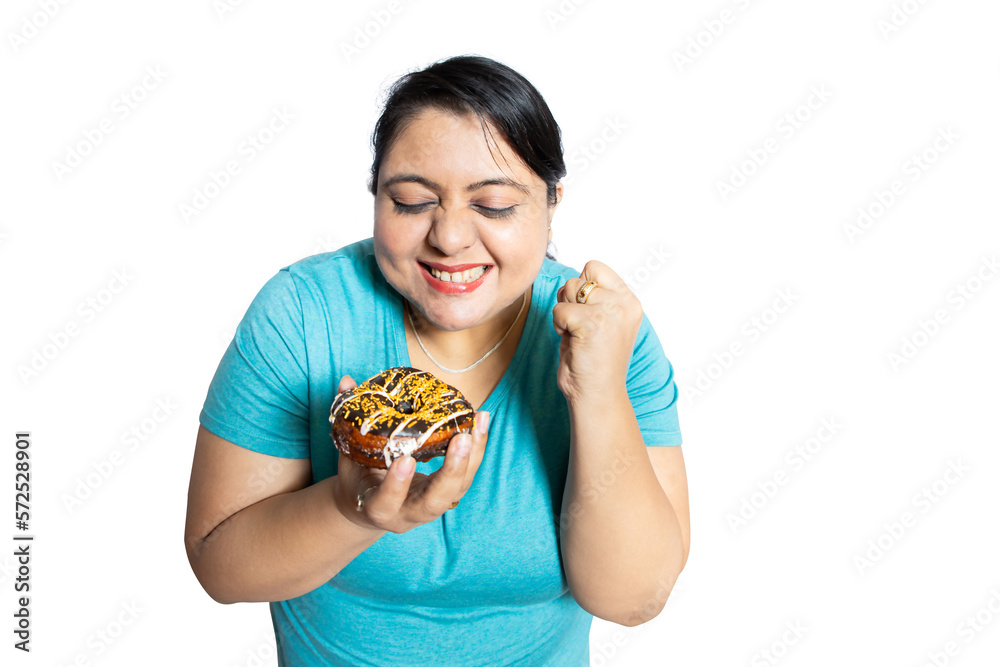 Overweight fat indian woman tempting to eat delicious chocolate donut isolated over white background,studio portrait. Overweight fat indian woman tempting to eat delicious chocolate donut isolated over white background,studio portrait.