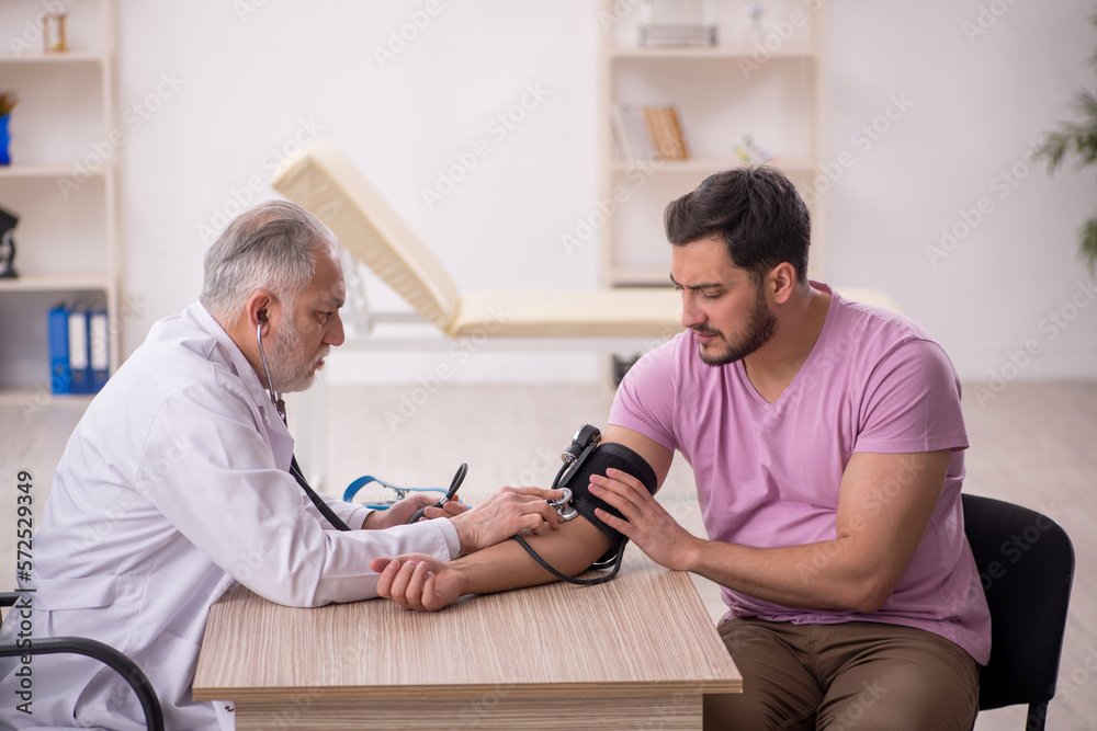 Old male doctor measuring young patient's blood pressure Old male doctor measuring young patient's blood pressure