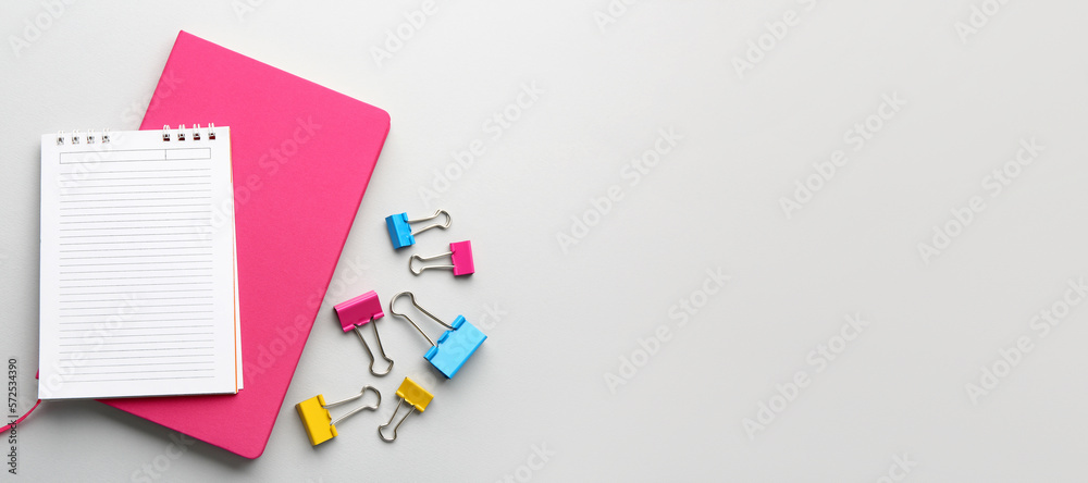 Notebooks and paper clips on light background with space for text