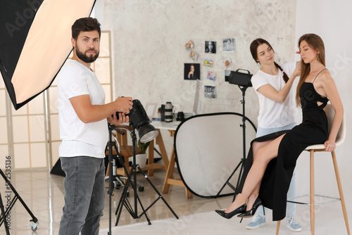 Male photographer and his assistant working with model in studio