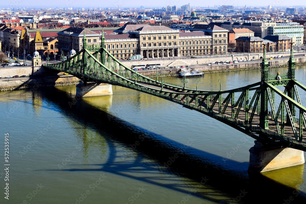 Fototapeta premium the Liberty bridge in Budapest over the Danube river. green steel suspension bridge. famous landmark and tourist attraction. The Great Market Hall in the background. travel and tourism in Europe