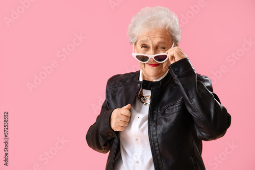 Foto Senior woman in sunglasses winking on pink background