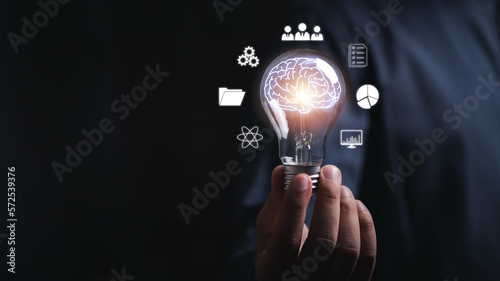 Cuadro en lienzo businessman Hand holding light bulb with brain glowing with orange light line and ray