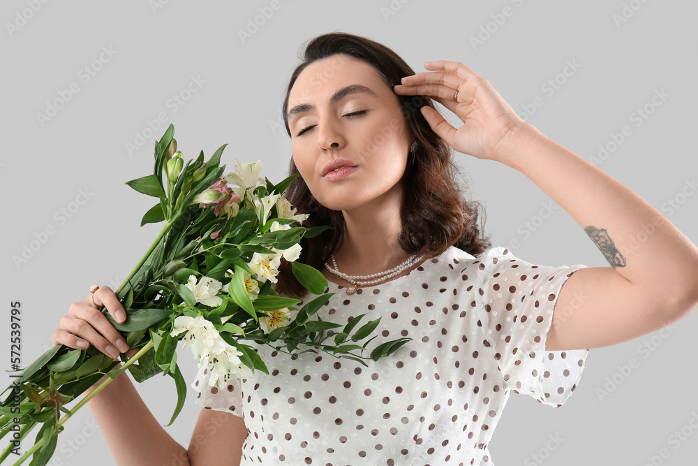 Young woman in dress with alstroemeria flowers on grey background Young woman in dress with alstroemeria flowers on grey background