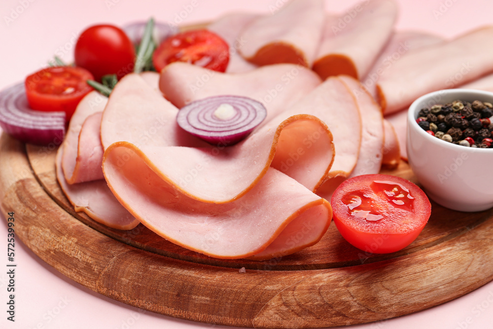 Board with tasty slices of ham, onion and tomatoes on pink background, closeup