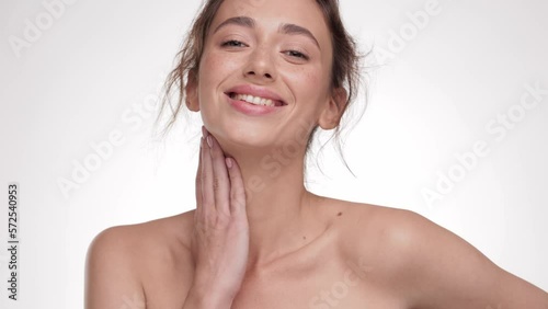 Close up Portrait Caucasian beauty face. Beautiful Woman touching her face skin. Female with fresh glowing hydrated facial skin and natural makeup on light background at studio. Skin care concept.