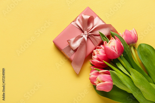 Gift box and beautiful tulip flowers on yellow background. Hello spring © Pixel-Shot