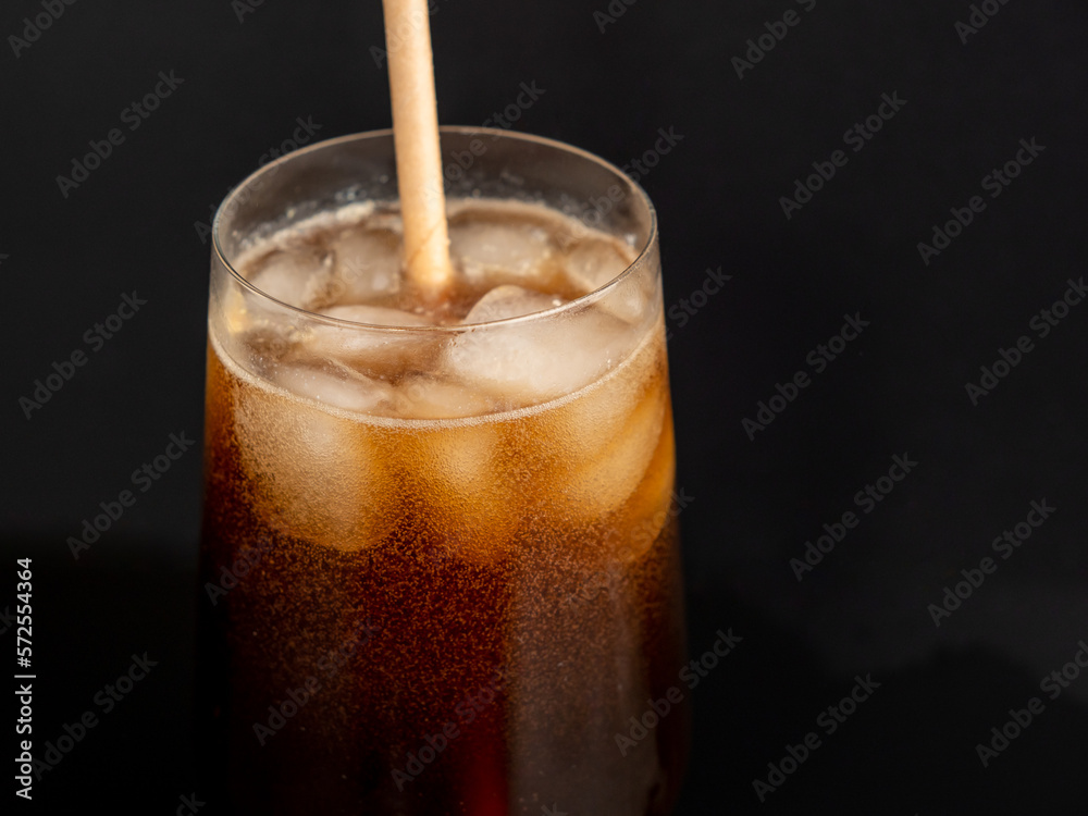 Glass of cola with ice on a black background. Close-up. Glass of cola with ice on a black background. Close-up.