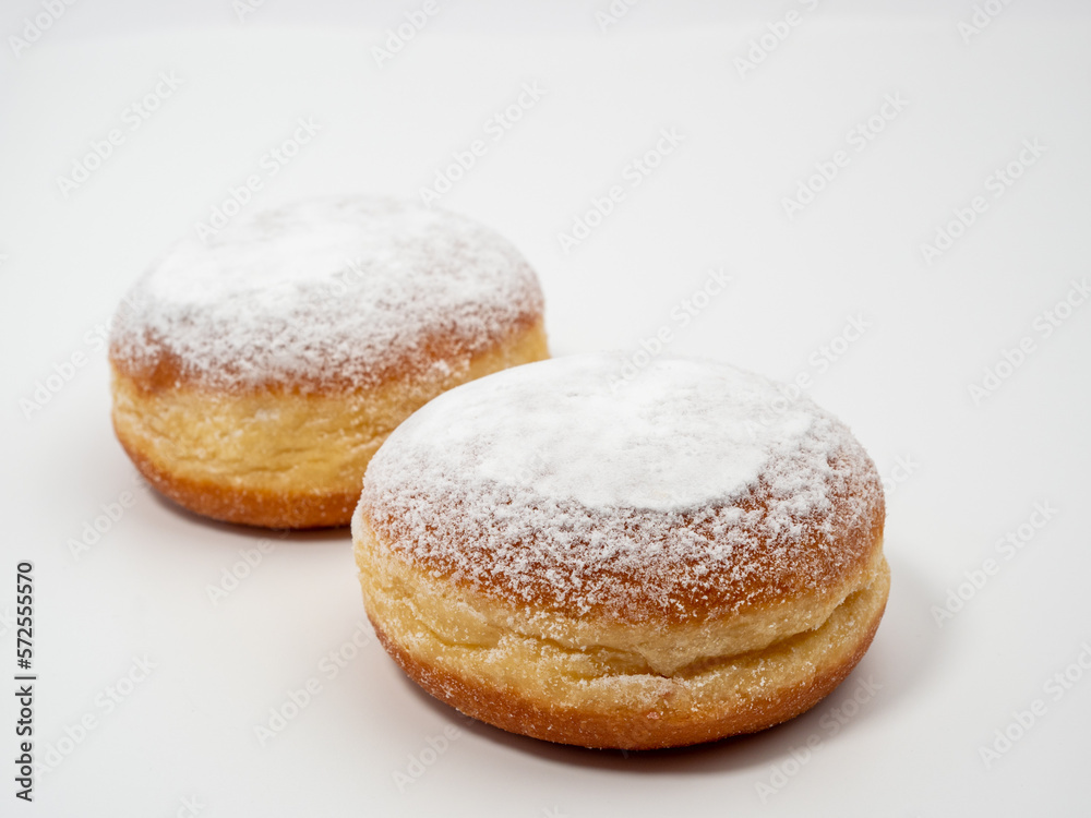 Freshly baked and dusted with powdered sugar German donuts. Donut berliner or krapfen on white background.