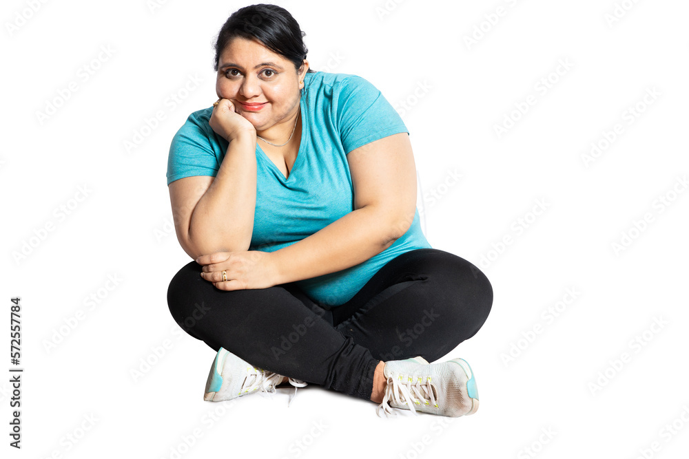 Smiling plus size indian woman sitting on floor isolated over white studio background looking at camera. Fat woman with positive expression on her face.
